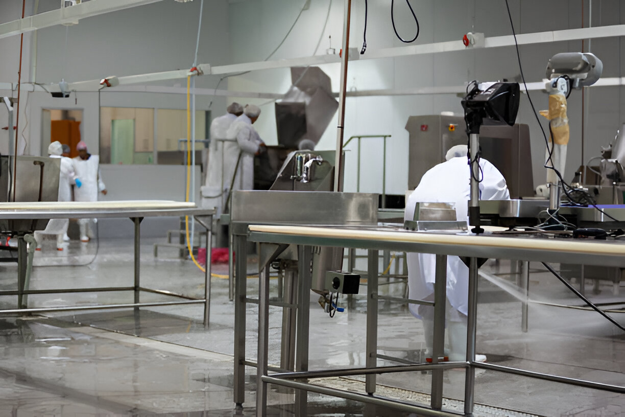 Travaux de maintenance industrielle dans une usine alimentaire, avec des techniciens effectuant un nettoyage approfondi et une désinfection des équipements pour garantir des standards d’hygiène élevés.